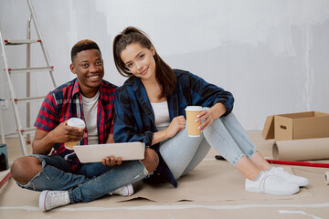Couple is spending time in new apartment redecorating room paint walls painting accessories...