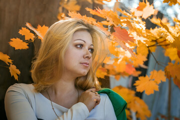 Portrait of a young beautiful blonde on the background of autumn leaves. thoughtful young woman looks in front of her