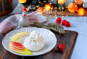 Buffalo Burrata cheese with pear. Traditional Italian, fresh, soft white cheese burrata ball of mozzarella and cream on a round light plate with slices of pear on the Christmas table 