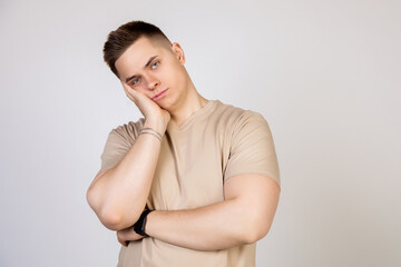 Obraz premium Young handsome guy holding his head with his hand, tired after a long and hard working day, standing on a white background looking at the camera