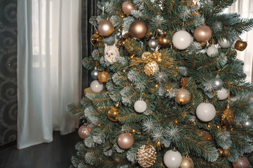 Christmas tree is decorated with bright shiny toys. Authentic view of the decorated Christmas tree on the background of the window