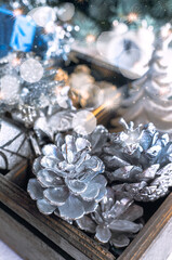 Decorative wooden box with Christmas tree toys and gift boxes. Silver toys with cones and shiny gift boxes. Christmas card