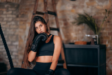 Beautiful young fitness girl posing at camera in black boxing glove
