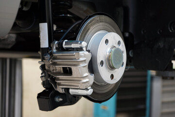 Fototapeta na wymiar Brake disc and brake caliper installed on a modern car. Selected focus. The background is blurred.