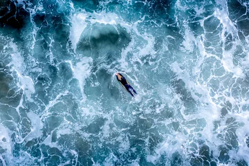 Fotobehang Aerial view of a surfers riding the waves in Newport Beach, California © Ben White/Wirestock