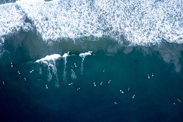 Aerial view of surfers riding the waves in Newport Beach, California - obrazy, fototapety, plakaty