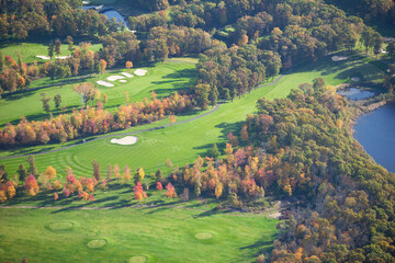 Aerial view of golf course and blue lake during autumn