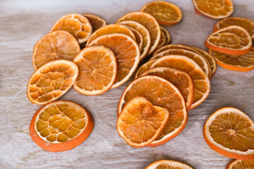 Fototapeta na wymiar Drying orange slices for handmade winter/ Christmas decorations: close-up of dried orange slices on baking sheet