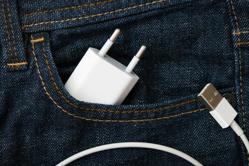 Usb charger, wire adapter for smartphone and gadgets in a jeans pocket taken on a trip