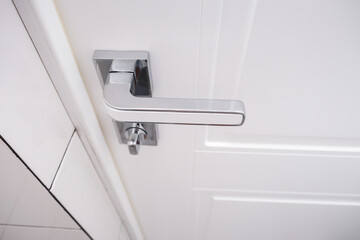 White wooden door with a chrome handle and safety security knob for privacy protection