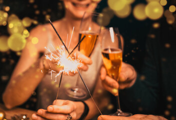 happy couple holding sparkles and champagne glasses New Year party