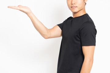 白い背景の前に立って、案内のポーズをする黒いTシャツを着ている男性