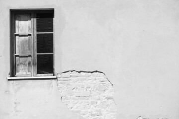 Grayscale shot of an old weathered wall and a window