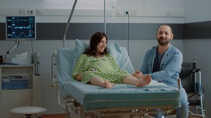 Young couple expecting baby in hospital ward clinic sitting together. Caucasian man and woman...