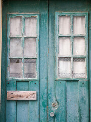 Portugal, Aveiro. Very old aqua wooden door with lace curtains in the windows.