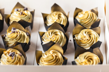 Birthday set of cupcakes in the white gift box with whipped cream top sprinkled with gold