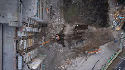 Excavator for dismantling buildings, using a special claw, dismantles a multi-storey building. View from above