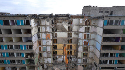 Excavator for dismantling buildings, using a special claw, dismantles a multi-storey building. View from above