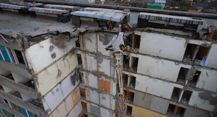Excavator for dismantling buildings, using a special claw, dismantles a multi-storey building. View from above