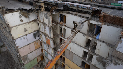 Excavator for dismantling buildings, using a special claw, dismantles a multi-storey building. View from above