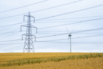Scenic view of a transmission tower and a windmill on the field