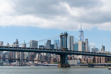 Obraz premium Brooklyn and Manhattan bridge with New York City financial downtown skyline panorama at day time over East River with blue cloudy sky.