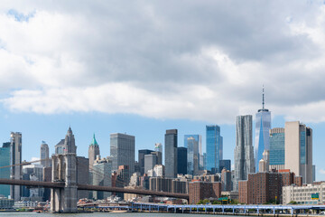 Brooklyn bridge with New York City Manhattan financial downtown skyline panorama at day time over East River with blue cloudy sky.