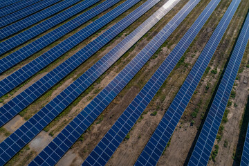 Solar power plant, solar panels shot from a drone, blue sky and clouds