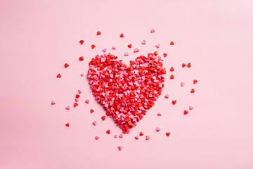 Valentines Day heart made of small red hearts on pink background. Creative layout, top view. Love, romance concept.