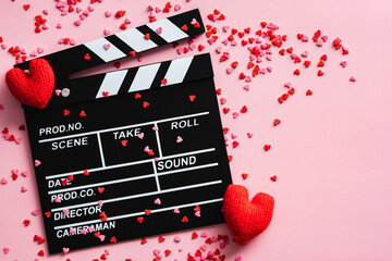 Movie clapper and Valentines Day hearts on pink background. Flat lay, top view. Love, romance...