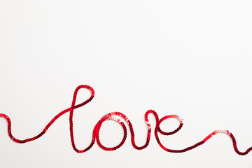 Love word made of red ribbon on white background. Abstract, flat lay. Happy Valentines Day concept.