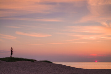 Fototapeta na wymiar Sweden, Scania, Malmo, Riberborgs Stranden beach area, woman exercising at sunset