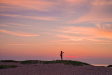 Fototapeta na wymiar Sweden, Scania, Malmo, Riberborgs Stranden beach area, woman photographing selfie at sunset