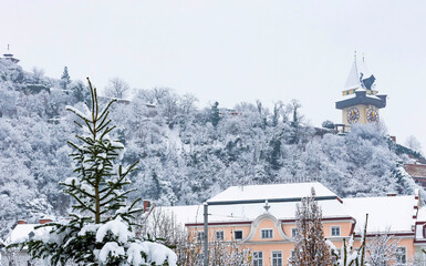 The famous clock tower on Schlossberg hill, in Graz, Steiermark region, Austria, with snow, in...