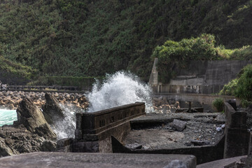 View of the empty shore with the wave hitting against rocks.