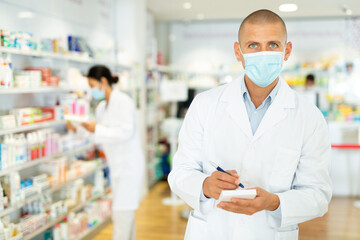 Portrait of an male pharmacist in protective mask, working in pharmacy during the pandemic;...