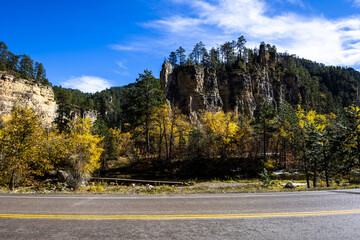 Spearfish Canyon with colorful trees and an empty road under a blue sky in South Dakota - obrazy, fototapety, plakaty