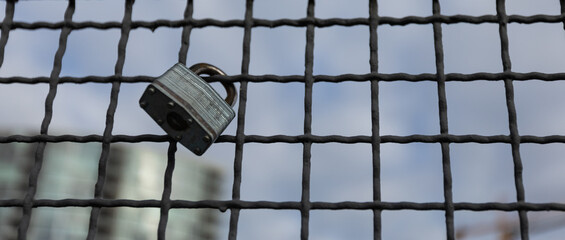 Obraz premium Padlocks hanging on a wire rope. Love locks on netting fence at the bridge in New Westminster BC.