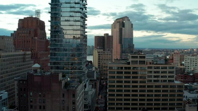 Descending aerial footage of high rise buildings in city. Glass facade reflecting twilight sky. Manhattan, New York City, USA