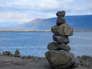 Fototapeta na wymiar Stone Carins with Faxafloi Harbor, Rainbow, and Mountians in Reykjavik Iceland
