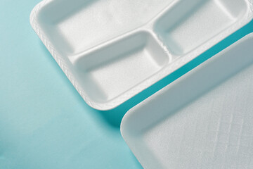 white Styrofoam plastic plates on blue background. Trash plastic, reusable plastic, disposable, for food.