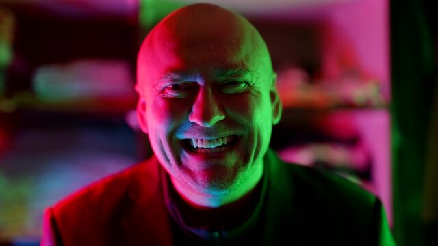 crazy man is laughing in nightclub, portrait in neon lights, mad smile and laugh