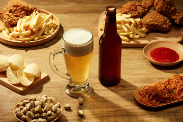 A glass and a bottle of beer with fried potatoes spicy chicken floss and fried chicken in brown...