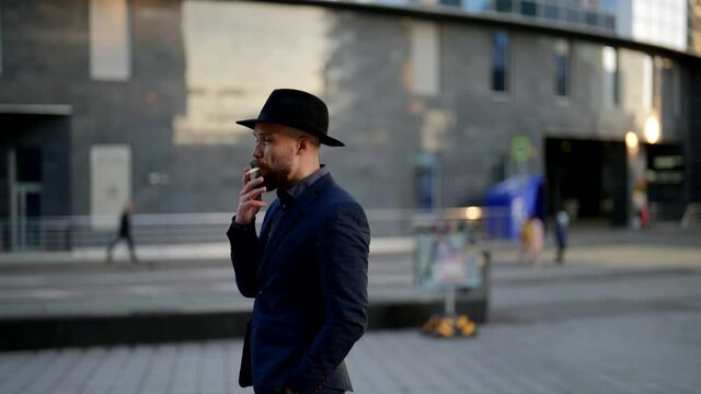funny shot with stylish man and hat blowed away by wind, person is walking in city