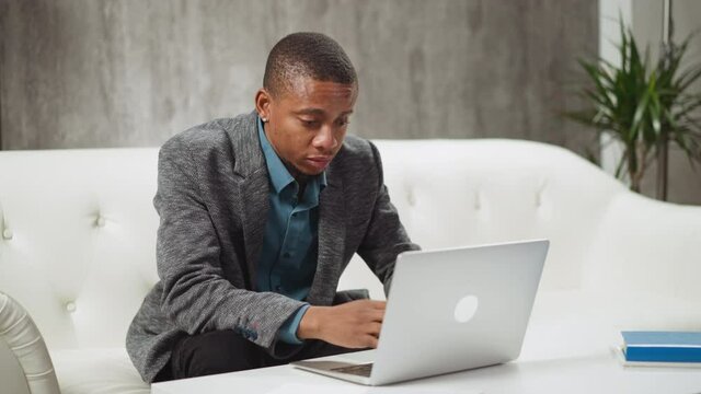 African-American private English lecturer professor delivers lecture to students at distant lesson via laptop computer at table in living room slow motion