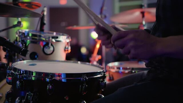 Closeup Caucasian man on lighted stage with drumsticks playing drums