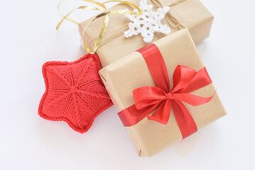 Christmas and New Years decorated gifts. Gift box wrapped in kraft paper with red ribbon. Red knitted heart. Box with jute cord and crocheted snowflake