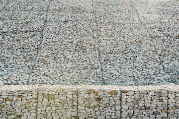 Granite stones behind a metal grate for strengthening the slope. Stones behind the wire. grey texture. construction.