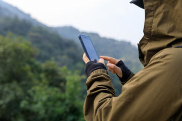 Successful hiker using smartphone on mountain top