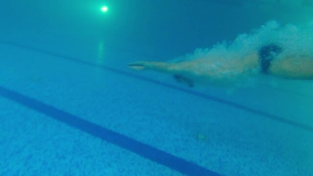 Young bearded man in indoor training pool - dive in the water and swimming underwater